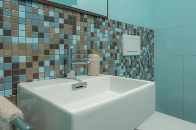 a white sink in a bathroom with a tiled wall at Luxury Apartment Nana in Bled