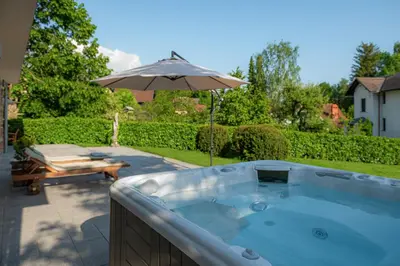 a hot tub with an umbrella in a yard at Luxury Apartment Nana in Bled