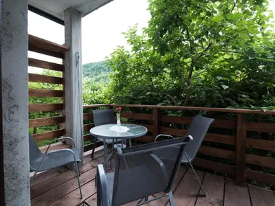a patio with a table and chairs on a deck at Apartma Matajurc in Trnovo ob Soči