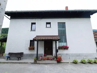 a white house with a bench in front of it at Apartma Matajurc in Trnovo ob Soči