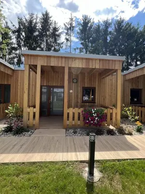 a small wooden building with a porch and flowers at Terme Paradiso - Hotel Paradiso in Dobova