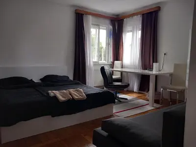 a bedroom with a bed and a table and a desk at Rooms & Apartments MURGLE Ljubljana in Ljubljana