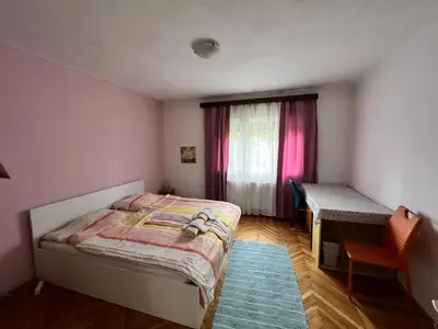 a bedroom with a bed and a desk and a window at Rooms & Apartments MURGLE Ljubljana in Ljubljana