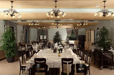 a dining room with white tables and chairs and chandeliers at Hotel Malovec in Divača