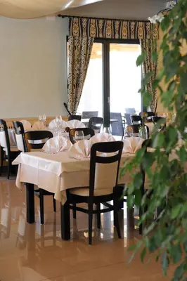 a dining room with tables and chairs and a window at Hotel Malovec in Divača