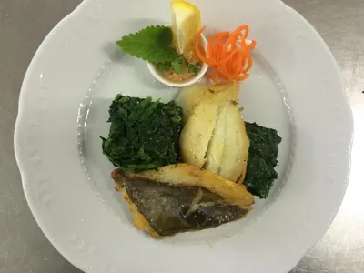 a plate of food with fish and vegetables on it at Hotel Malovec in Divača