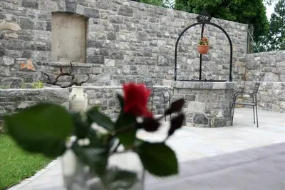 a red flower in a vase next to a brick wall at Hotel Malovec in Divača