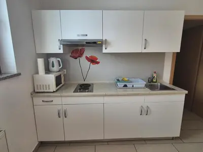 a kitchen with white cabinets and a sink and a microwave at Apartments Furman - SELF CHECK-IN in Rakek