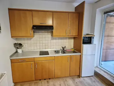 a kitchen with wooden cabinets and a sink and a refrigerator at Apartment Paradise in Moravske Toplice