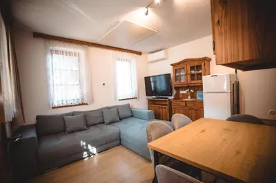 a living room with a blue couch and a kitchen at POČITNIŠKI APARTMAJI - Sunny apartment in Moravske Toplice in Moravske Toplice