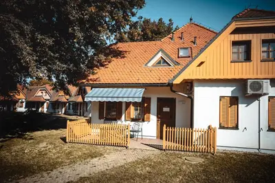 a white house with an orange roof and a fence at POČITNIŠKI APARTMAJI - Sunny apartment in Moravske Toplice in Moravske Toplice