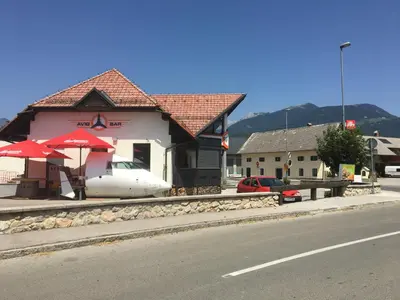 a building with a table and umbrellas on the side of a street at Apartments Avio in Zgornji Brnjik