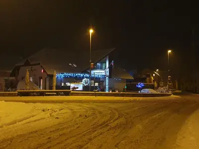 a building on a snowy street at night at Apartments Avio in Zgornji Brnjik