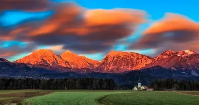 a view of a mountain range with a house in a field at Apartments Avio in Zgornji Brnjik