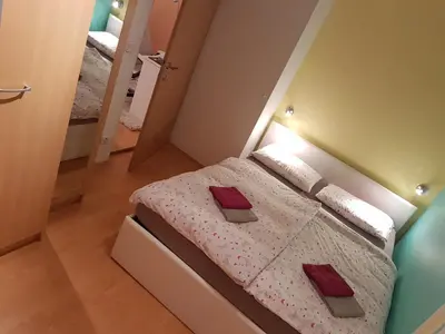 a bedroom with a bed with white sheets and red pillows at Apartments Lake Bohinj Medja in Bohinj