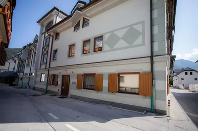 a white building with brown doors on a street at Apartment Tinka Kranjska Gora in Kranjska Gora