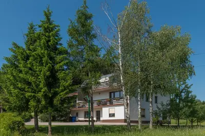 a white building with trees in front of it at Apartment - Speleo Camp in Logatec