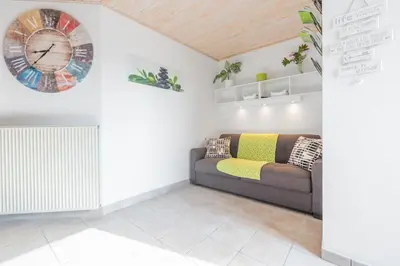 a living room with a couch and a clock on the wall at Apartment - Speleo Camp in Logatec