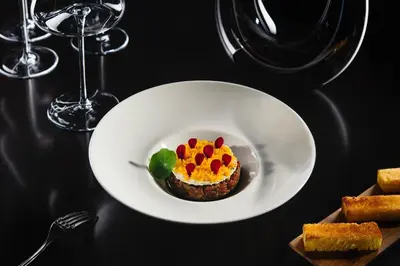 a white plate with a dessert on a table with wine glasses at Hotel Aleksander Medical & SPA in Rogaška Slatina