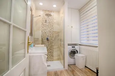 a bathroom with a shower and a sink and a washing machine at Sweet 16 Studio in Ljubljana