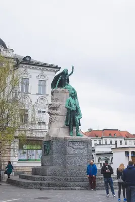 a statue in front of a building with people standing around it at Sweet 16 Studio in Ljubljana
