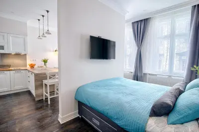 a white bedroom with a bed and a kitchen at Sweet 16 Studio in Ljubljana