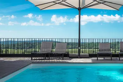 a swimming pool with two chairs and an umbrella at Fana Estate in Dobrovo