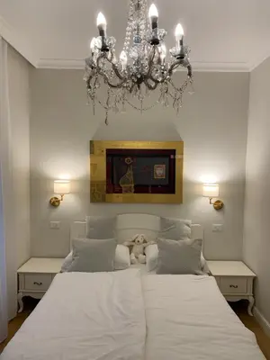 a bedroom with a large white bed with a chandelier at FORUM Apartment I and II in Ljubljana