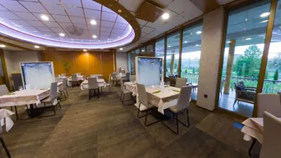a restaurant with white tables and chairs and windows at Hotel Venko in Dobrovo
