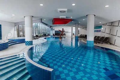 a large swimming pool with blue tiles in a building at Hotel Zagreb - Health & Beauty in Rogaška Slatina