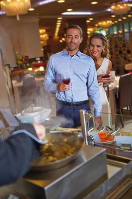 a man and a woman standing behind a buffet at Hotel Zagreb - Health & Beauty in Rogaška Slatina