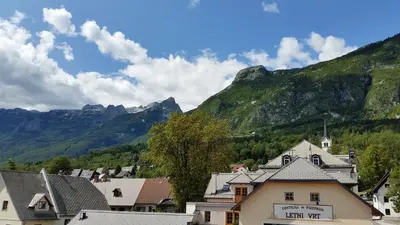 a town with mountains in the background with houses at Thirsty River Rooms in Bovec