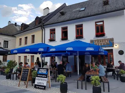 a group of people sitting at tables under blue umbrellas at Thirsty River Rooms in Bovec