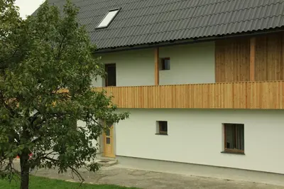 a white building with a wooden fence on the side at Apartments Arh in Bohinjska Bistrica