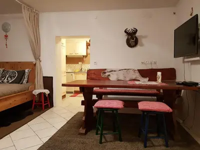 a living room with a table and two stools at Zajček Apartma in Mojstrana