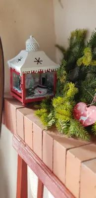a small christmas decoration on a brick ledge with a christmas tree at Zajček Apartma in Mojstrana