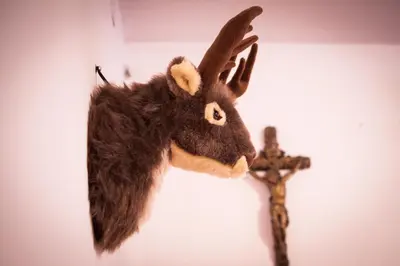 a stuffed moose head on a wall next to a cross at Zajček Apartma in Mojstrana