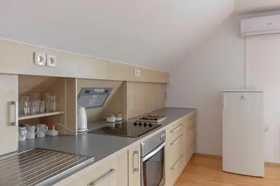 a kitchen with wooden cabinets and a white refrigerator at Apartment Tati in Dol pri Ljubljani