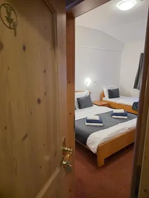 two beds in a room with a door open at Hotel Rakov Skocjan in Cerknica