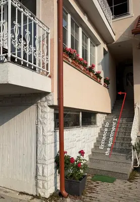 a building with stairs and a balcony with flowers at Apartments Žnidar in Spodnje Gorje