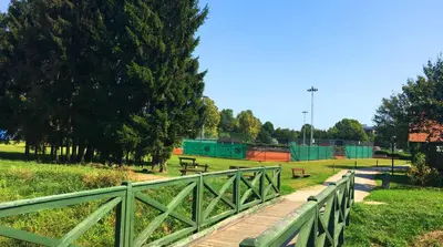 a wooden bridge in a park with benches and trees at Apartment Marjetica in Moravske Toplice