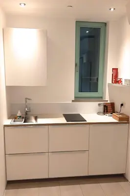 a kitchen with white cabinets and a sink and a mirror at i Design Studio in Ljubljana