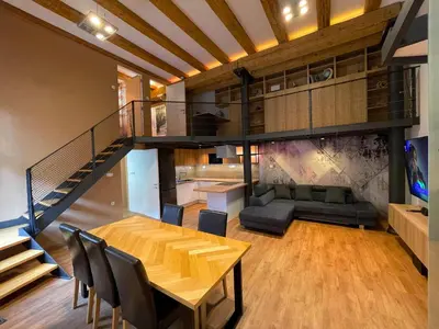 a living room with a wooden table and a staircase at Gami Ex-Factory Lofts in Ljubljana