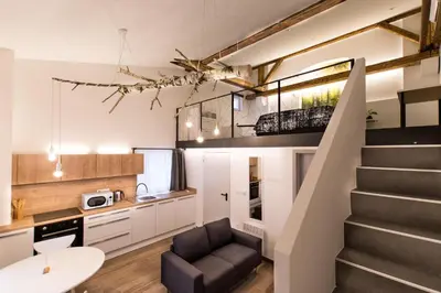 a staircase in a living room with a couch and a kitchen at Gami Ex-Factory Lofts in Ljubljana