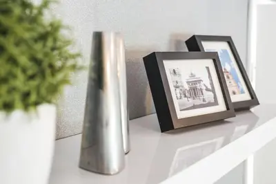 a white shelf with two pictures and a vase on it at Apartment Mario in Ptuj