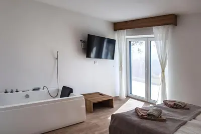 a white bathroom with a tub and a tv on the wall at Vila Marin Miler in Prevalje