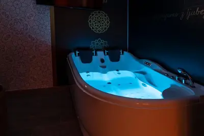 a bath tub in a bathroom with a blue sink at Vila Marin Miler in Prevalje