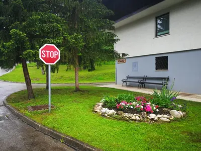 a stop sign in front of a garden with flowers at Planika B&M in Bohinj