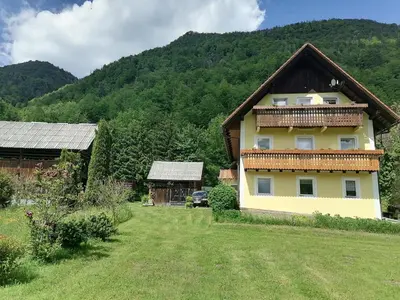a house in the middle of a yard with a mountain at Apartment House Andrej in Bohinj