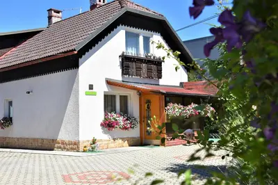 a white house with a balcony and flowers at Apartma Franko in Cerklje na Gorenjskem